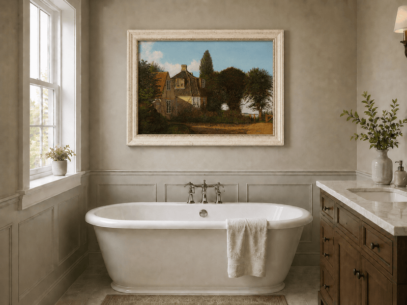 Framed hand-painted rural cottage oil painting with half-timbered walls, tiled roofs and trees displayed above a freestanding bathtub.