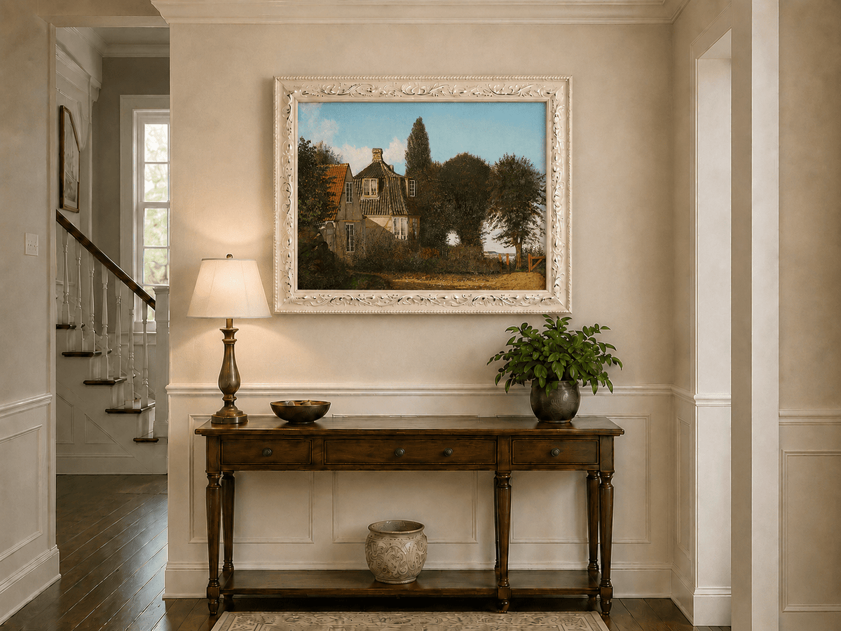 Framed hand-painted rural cottage oil painting with half-timbered walls, tiled roofs and trees displayed above an entryway console table.