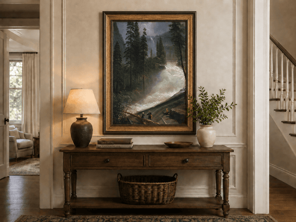 Framed hand-painted forest oil painting with figures beside a rushing river and waterfall displayed above an entryway console table.