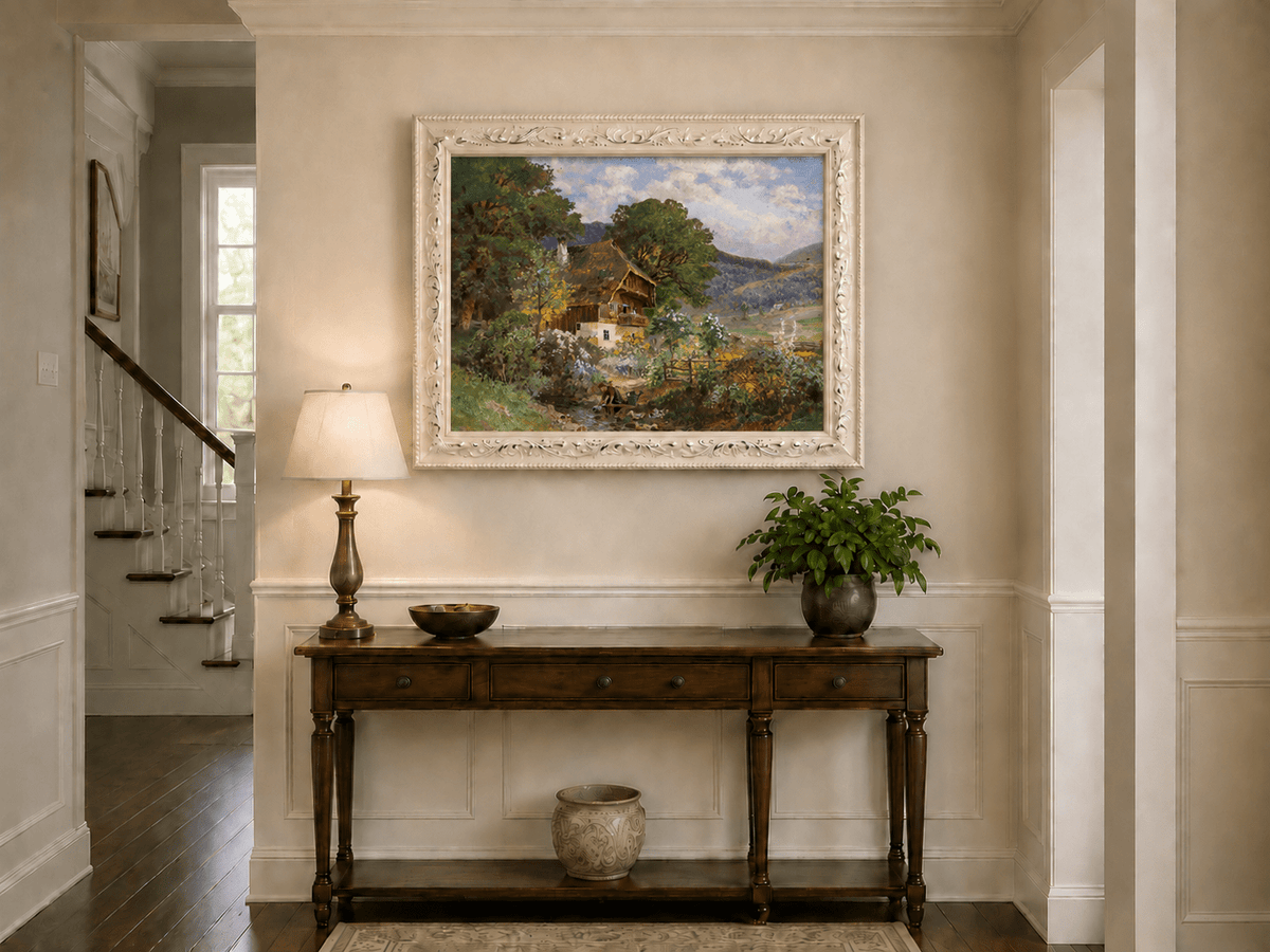 Framed hand-painted rustic cottage oil painting in a colorful mountain valley displayed above an entryway console table.