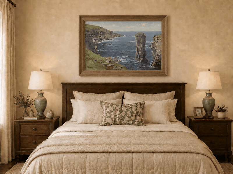 Framed hand-painted coastal oil painting with sea stacks, cliffs and churning ocean waves displayed above a wooden bed in a neutral bedroom.