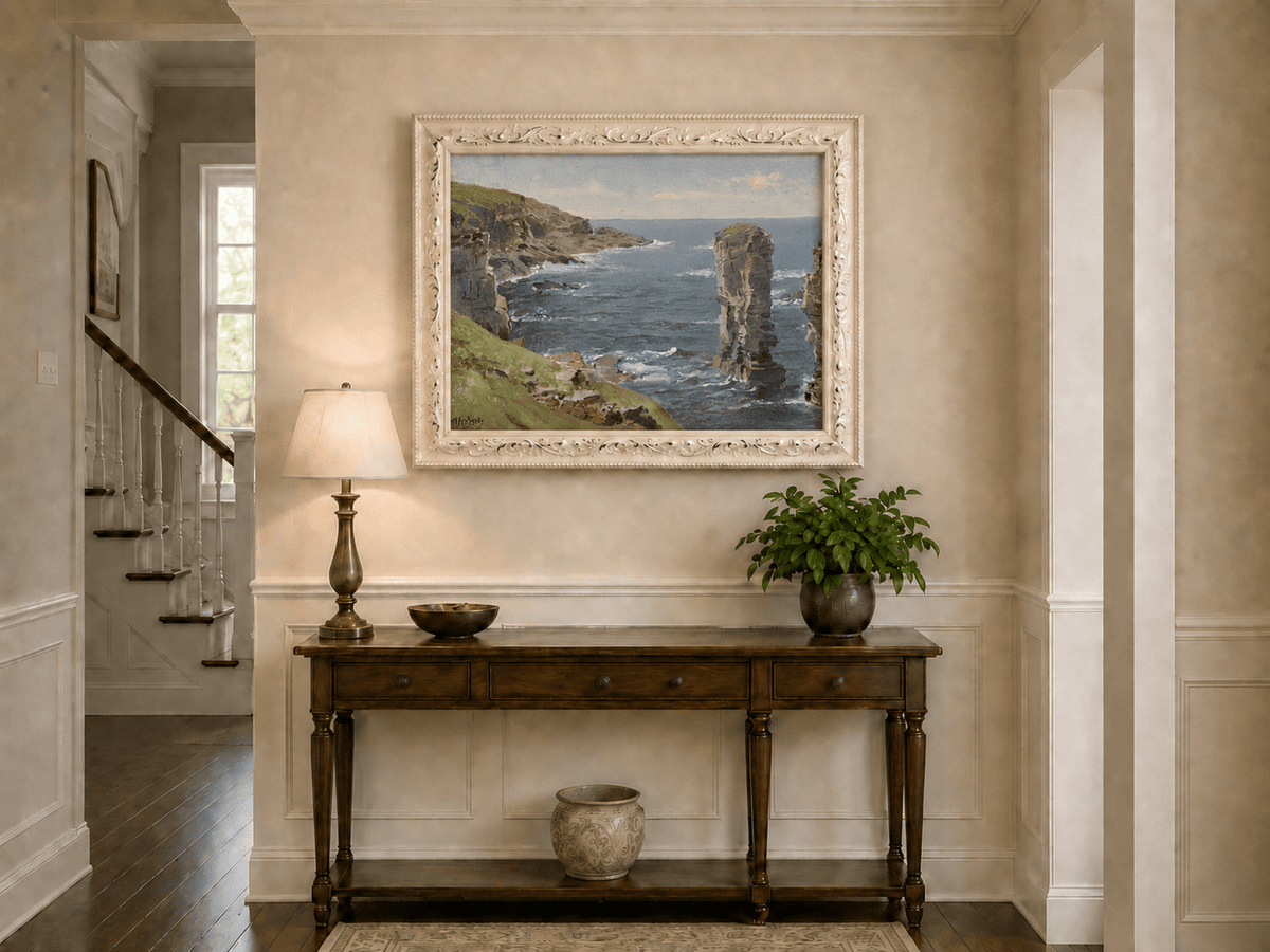 Framed hand-painted coastal oil painting with sea stacks, cliffs and churning ocean waves displayed above an entryway console table.