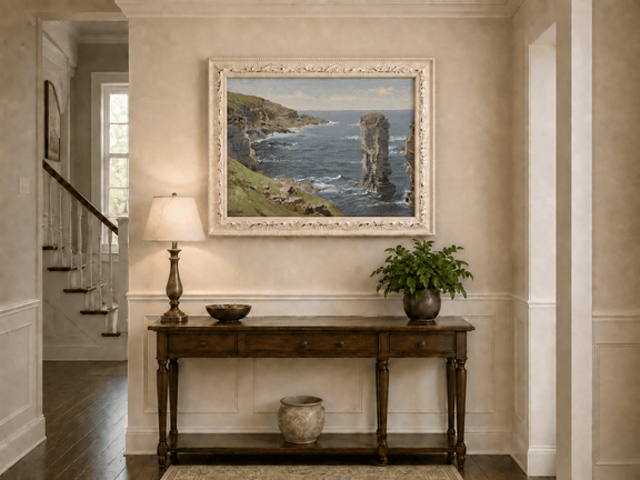 Framed hand-painted coastal oil painting with sea stacks, cliffs and churning ocean waves displayed above an entryway console table.