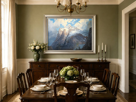 Framed hand-painted snow-capped mountain oil painting rising through luminous mist displayed above a formal dining table.