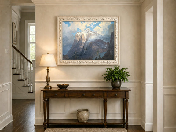 Framed hand-painted snow-capped mountain oil painting rising through luminous mist displayed above an entryway console table.