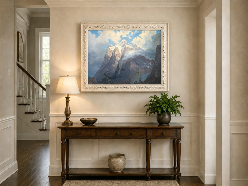 Framed hand-painted snow-capped mountain oil painting rising through luminous mist displayed above an entryway console table.