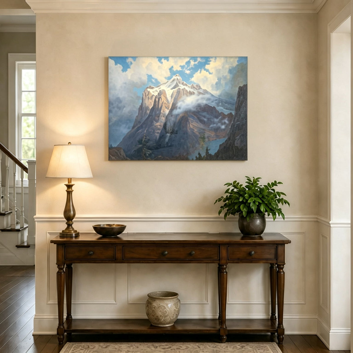 Unframed hand-painted snow-capped mountain oil painting rising through luminous mist displayed above an entryway console table.
