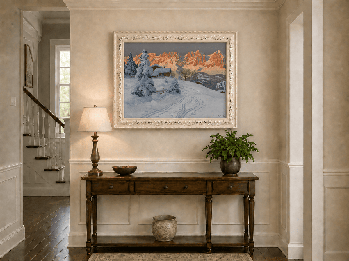 Framed hand-painted winter alpine oil painting with a snowy cabin and mountains at sunset displayed above an entryway console table.