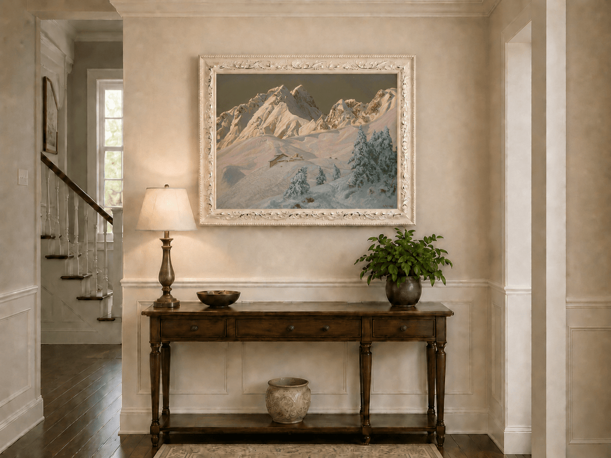 Framed hand-painted alpine oil painting with snowy mountain peaks glowing at dawn displayed above an entryway console table.