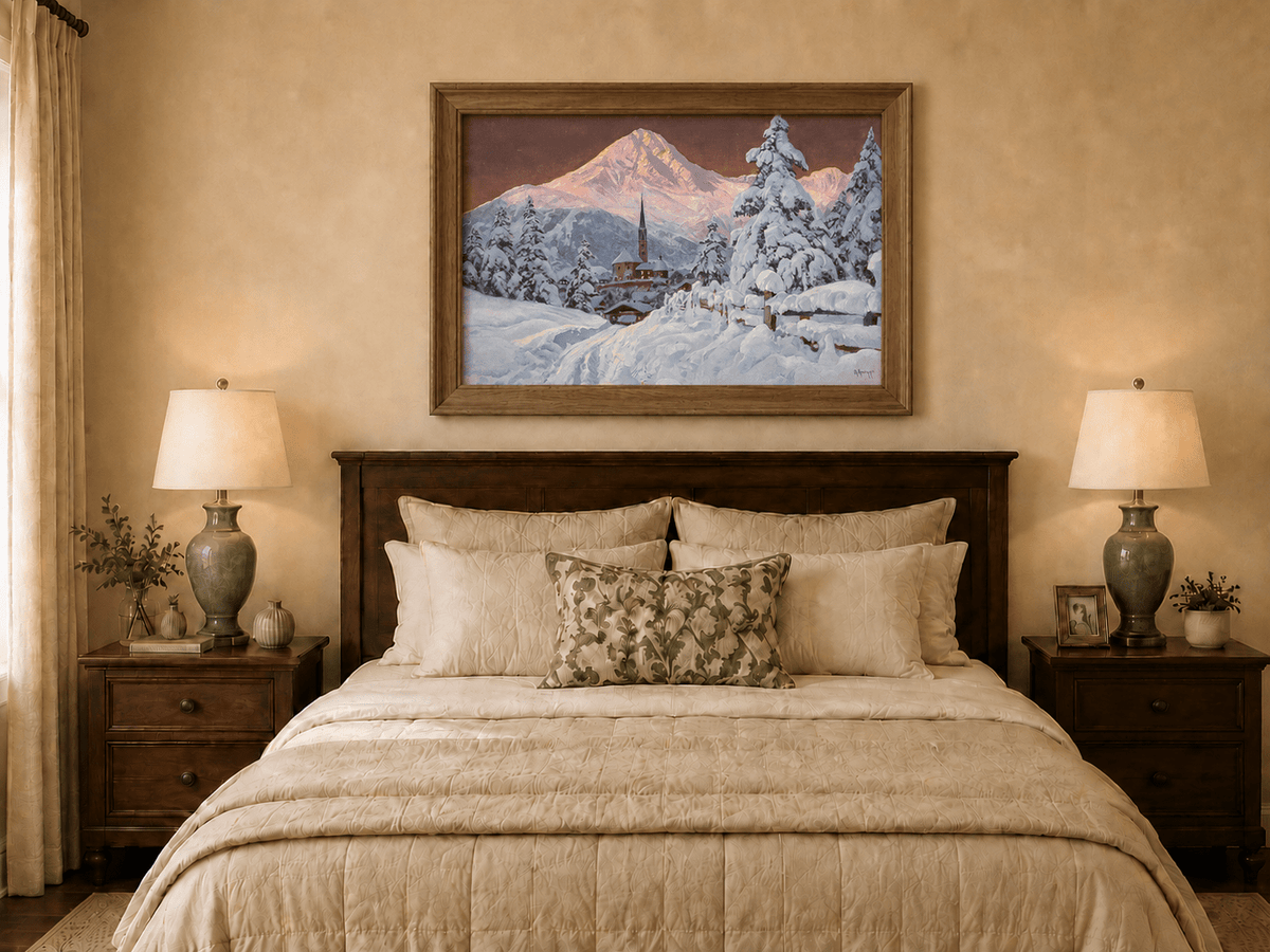 Framed hand-painted snowy alpine village oil painting with a church and pink mountain peaks displayed above a wooden bed in a neutral bedroom.