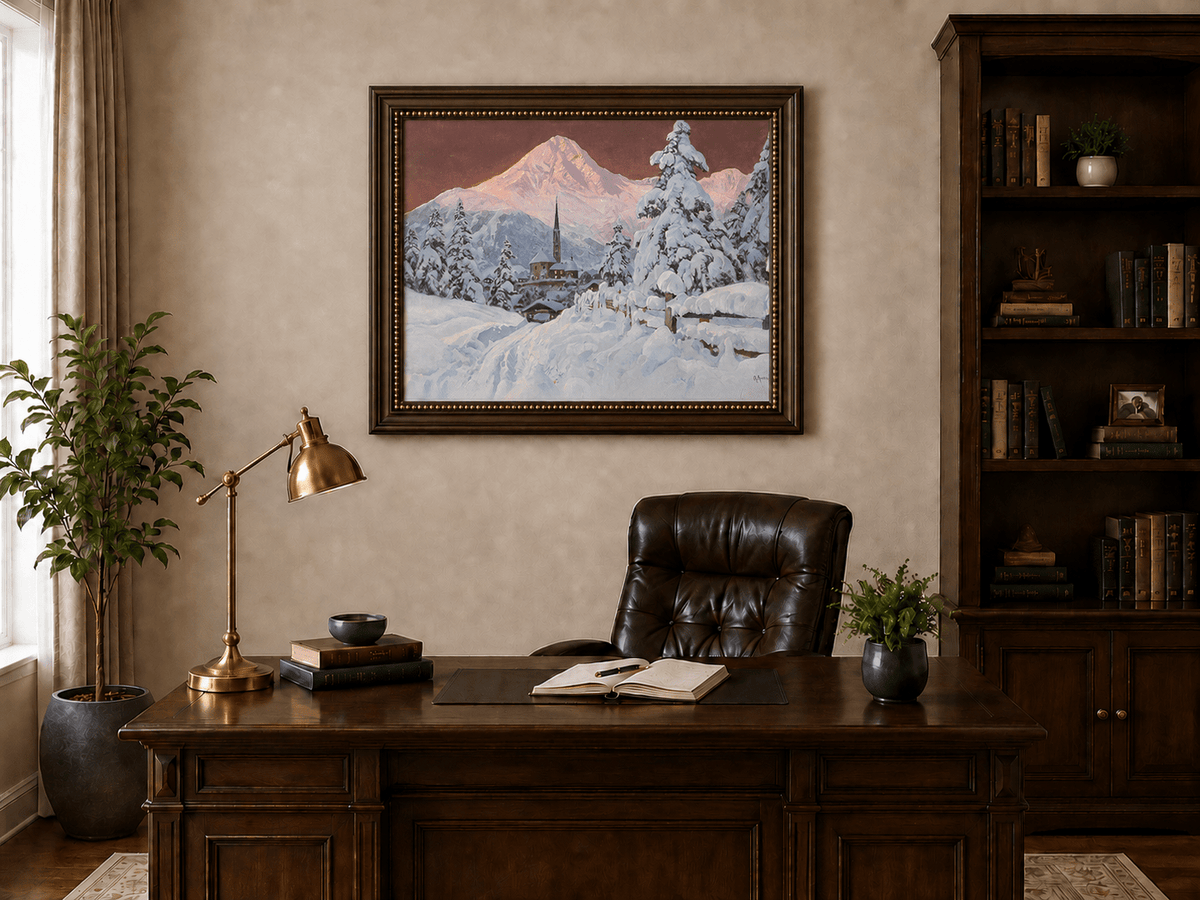 Framed hand-painted snowy alpine village oil painting with a church and pink mountain peaks displayed above a traditional home office desk.