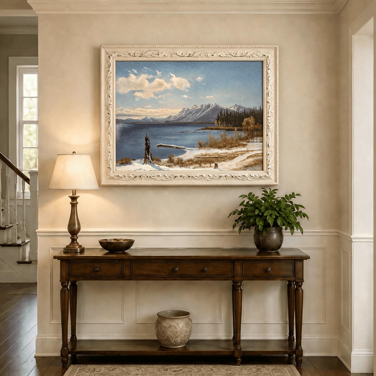 Framed hand-painted snowy lake oil painting with a winter path and distant mountain view displayed above an entryway console table.