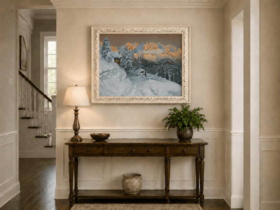 Framed hand-painted winter mountain oil painting with a snowy hut and tracks displayed above an entryway console table.