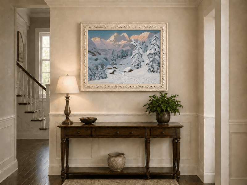 Framed hand-painted winter mountain oil painting with snowy huts and tracks displayed above an entryway console table.
