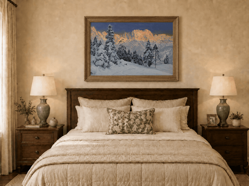 Framed hand-painted winter mountain oil painting with snow-covered pine trees and footprints displayed above a wooden bed in a neutral bedroom.