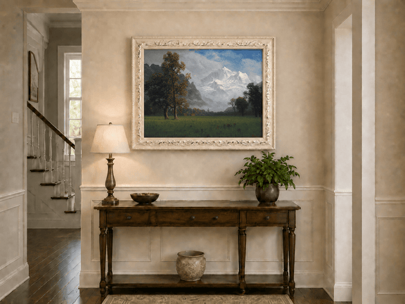 Framed hand-painted snowy mountain valley oil painting with a meadow and tall trees displayed above an entryway console table.