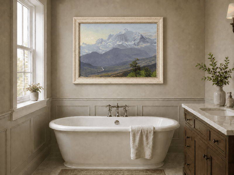 Framed hand-painted snowy mountain valley oil painting with a winding river and rolling hills displayed above a freestanding bathtub.
