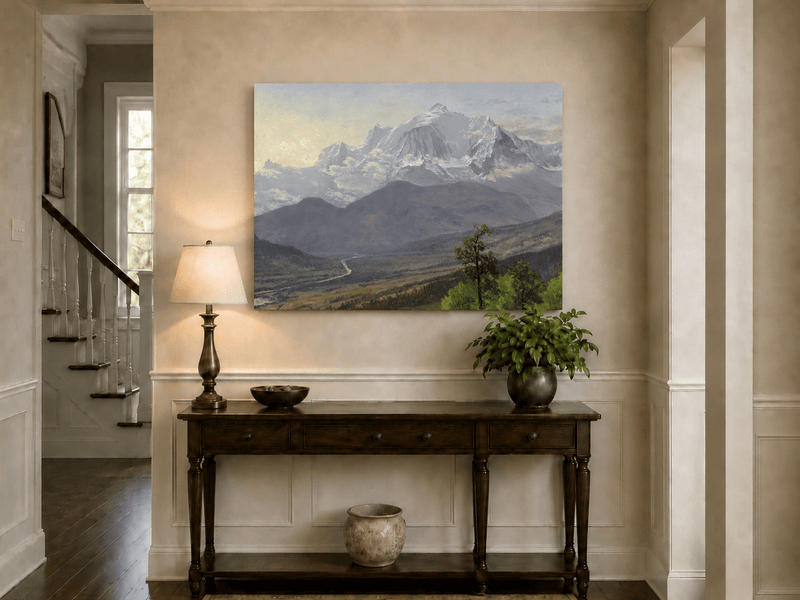 Unframed hand-painted snowy mountain valley oil painting with a winding river and rolling hills displayed above an entryway console table.
