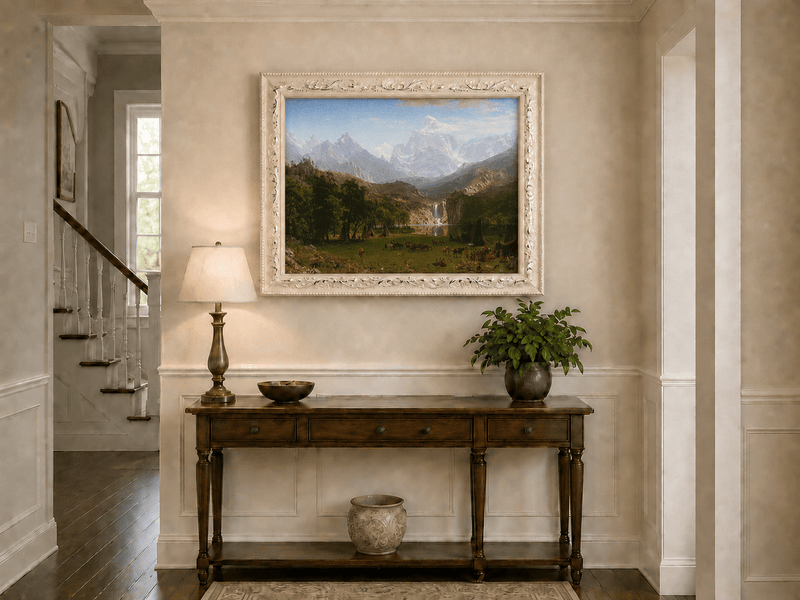 Framed hand-painted mountain landscape oil painting with snowy peaks, a lake and teepee camp displayed above an entryway console table.