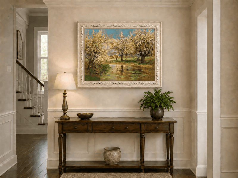 Framed hand-painted spring orchard oil painting with blossoming trees around a quiet pond displayed above an entryway console table.