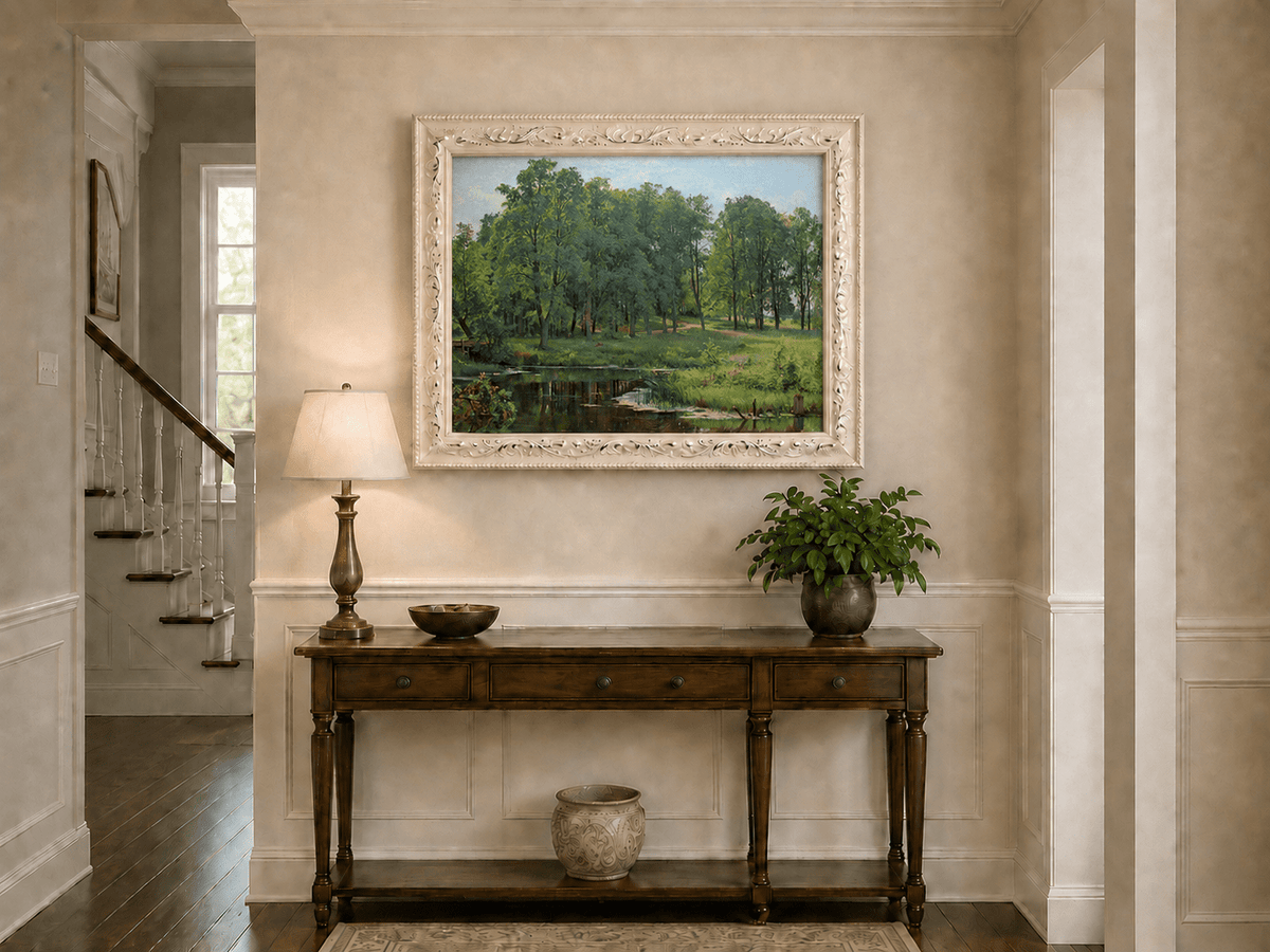 Framed hand-painted summer forest oil painting with a river, path and lush green trees displayed above an entryway console table.