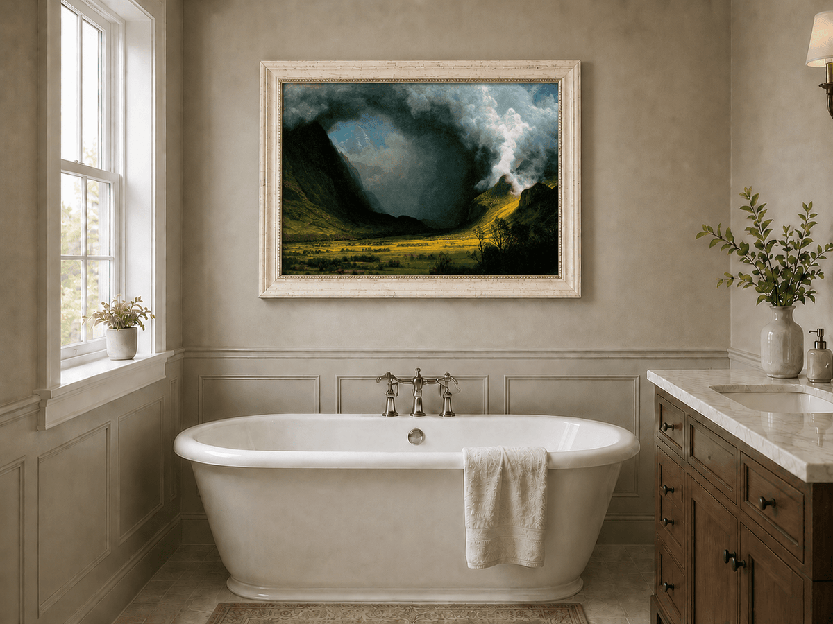 Framed hand-painted landscape oil painting with sunlight beneath dramatic storm clouds displayed above a freestanding bathtub.