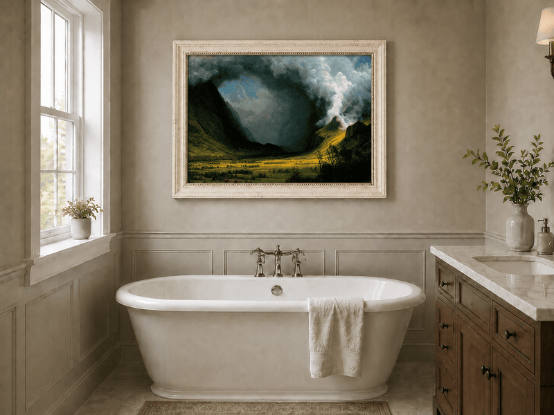 Framed hand-painted landscape oil painting with sunlight beneath dramatic storm clouds displayed above a freestanding bathtub.