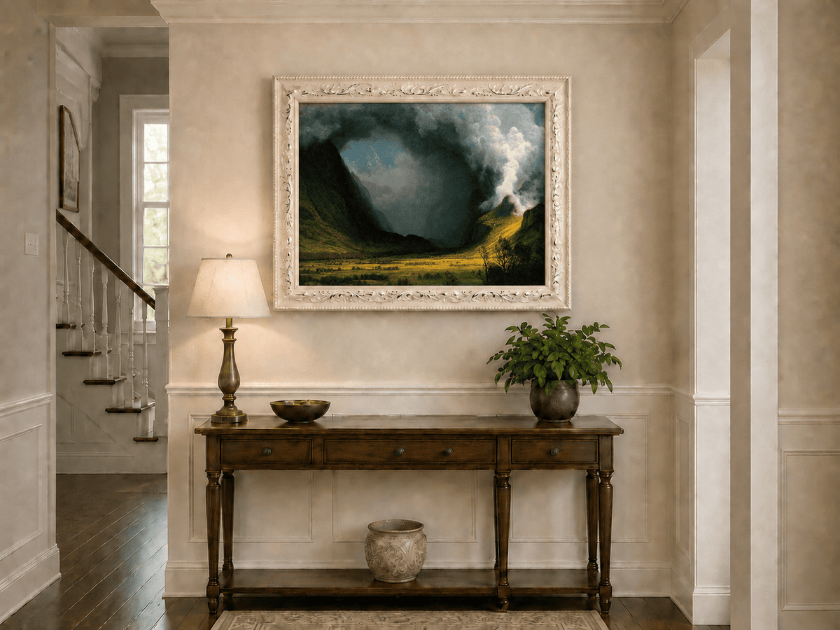 Framed hand-painted landscape oil painting with sunlight beneath dramatic storm clouds displayed above an entryway console table.