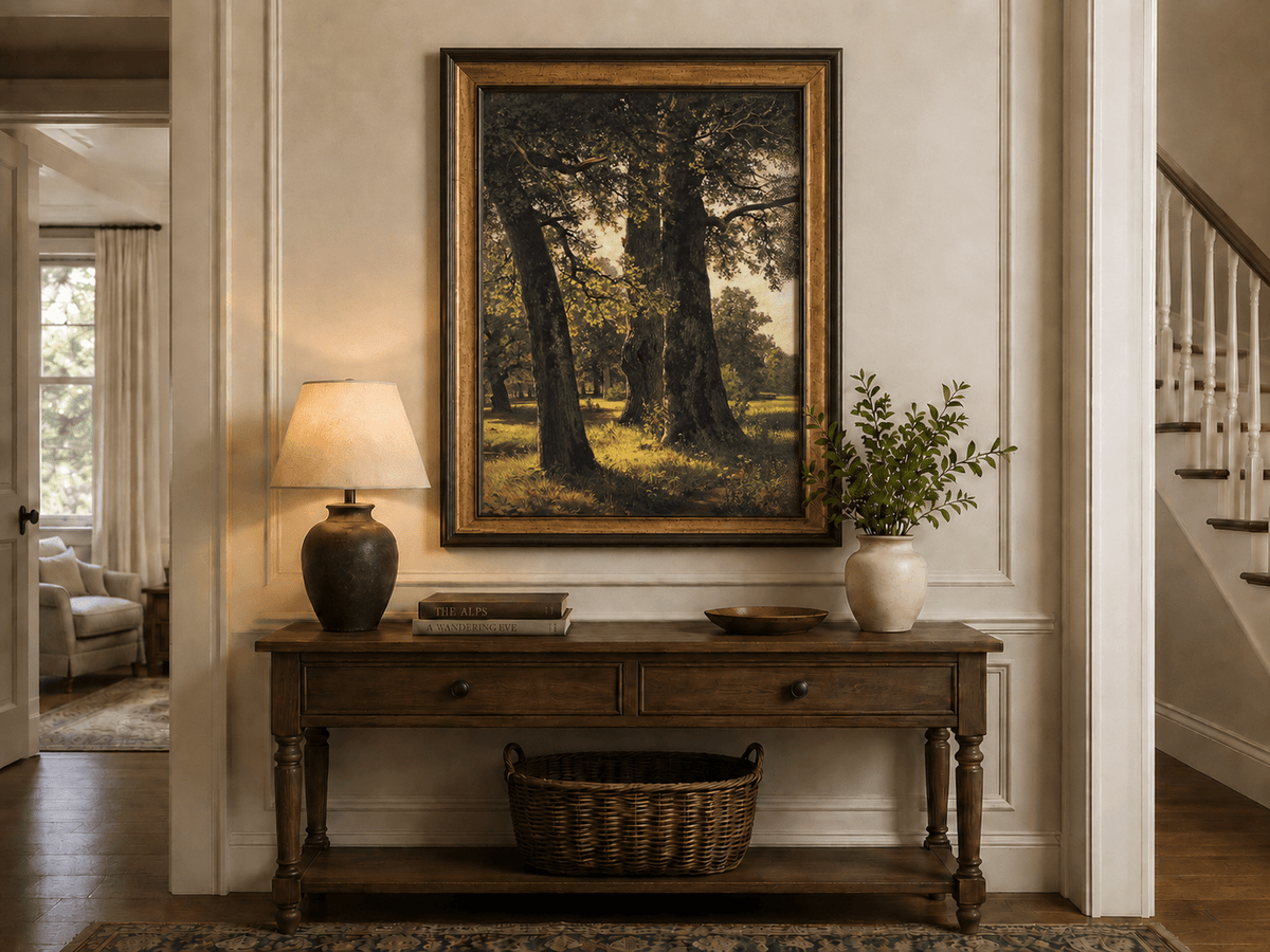 Framed hand-painted sunlit forest oil painting with massive ancient trees and golden ground displayed above an entryway console table.