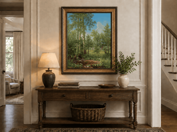 Framed hand-painted sunlit forest oil painting with a stream and wildflower glade displayed above an entryway console table.