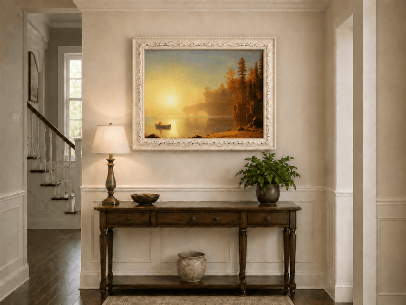 Framed hand-painted sunset lake oil painting with a canoe on glowing water displayed above an entryway console table.