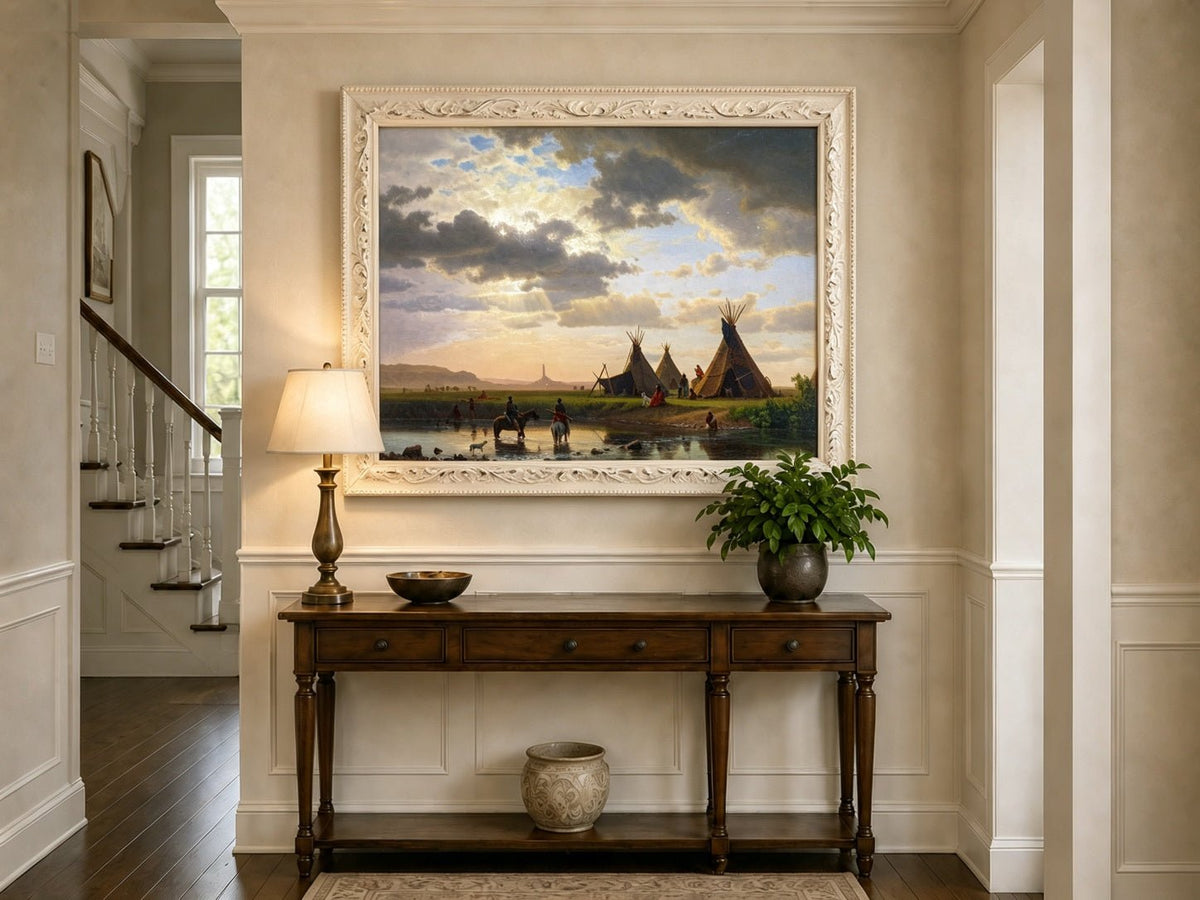 Framed hand-painted sunset river camp oil painting with tipis and riders crossing the water displayed above an entryway console table.