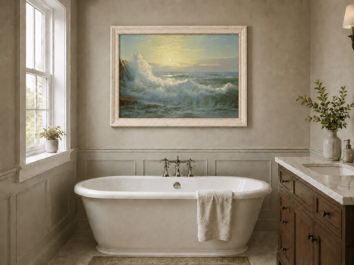Framed hand-painted sunset seascape oil painting with luminous crashing waves displayed above a freestanding bathtub.