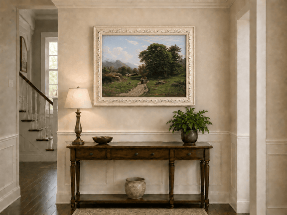 Framed hand-painted Swiss landscape oil painting with a country path, trees and distant peaks displayed above an entryway console table.