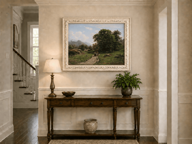 Framed hand-painted Swiss landscape oil painting with a country path, trees and distant peaks displayed above an entryway console table.