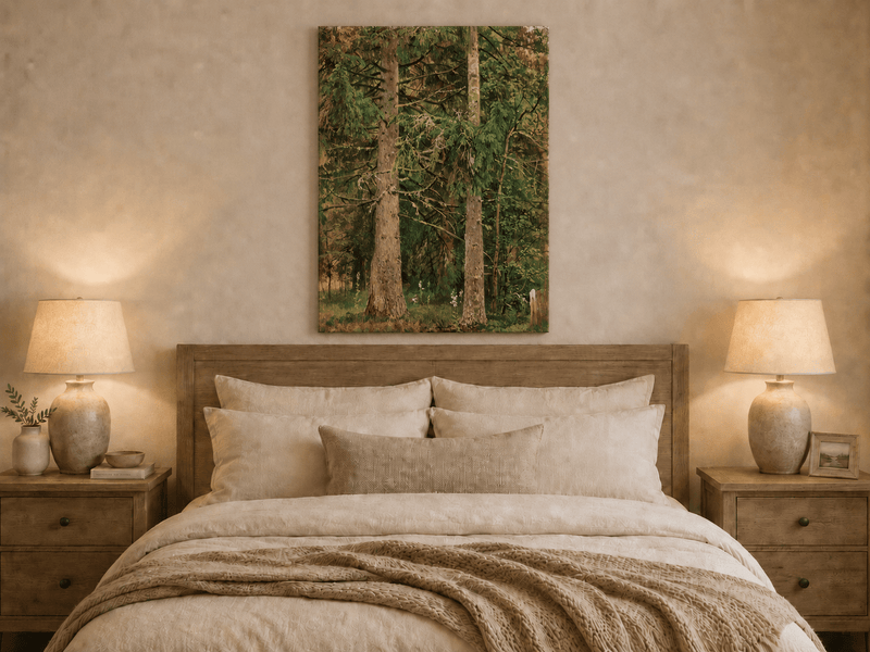 Unframed hand-painted tall pine forest oil painting with lush green undergrowth displayed above a wooden bed in a neutral bedroom.