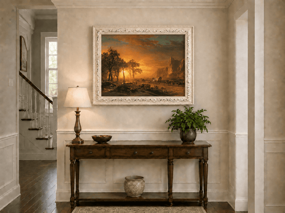 Framed hand-painted western landscape oil painting with travelers journeying at sunset displayed above an entryway console table.
