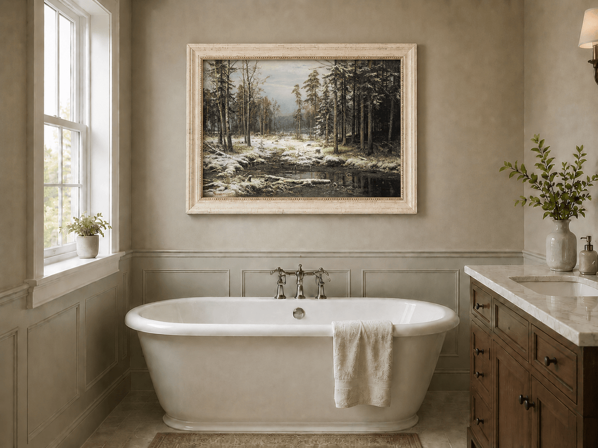 Framed hand-painted winter forest oil painting with a flowing stream through snowy woods displayed above a freestanding bathtub.