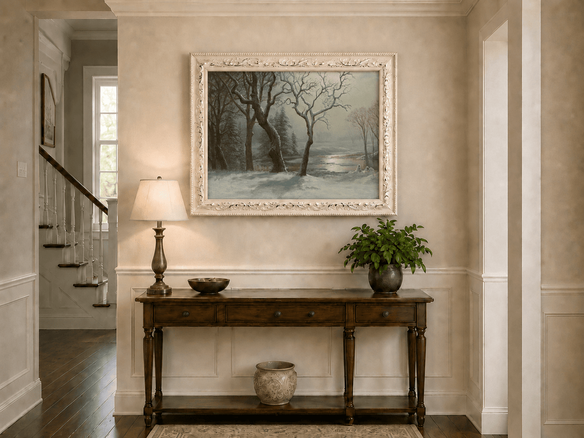 Framed hand-painted winter river oil painting with bare trees in a snowy forest displayed above an entryway console table.
