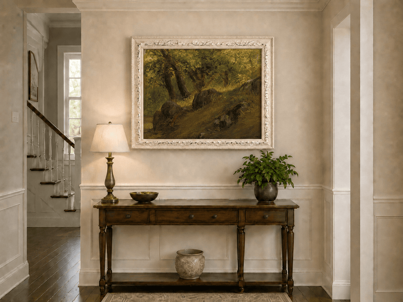 Framed hand-painted wooded hillside oil painting with mossy rocks and sunlit trees displayed above an entryway console table.